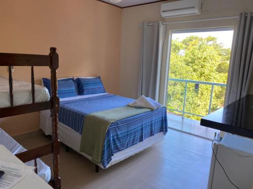 a bedroom with a bed and a window with a balcony at Pousada Colibri in Trindade