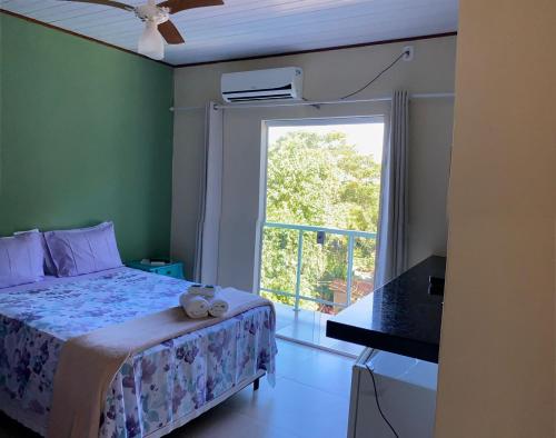 a bedroom with a bed and a large window at Pousada Colibri in Trindade