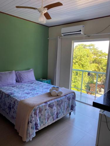 a bedroom with a bed and a large window at Pousada Colibri in Trindade