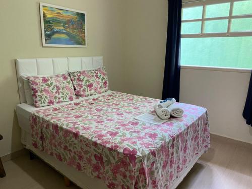 a bedroom with a bed with a pink bedspread and a window at Pousada Colibri in Trindade