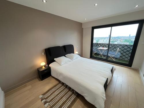 a bedroom with a large bed and a large window at Le Richelieu in Courbevoie