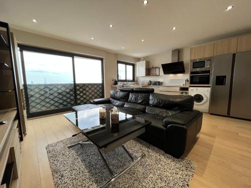 un salon avec un canapé en cuir noir et une table dans l'établissement Le Richelieu, à Courbevoie