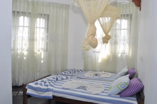 1 dormitorio con 1 cama con cortinas y ventanas blancas en Marshal Beach Guesthouse, en Negombo