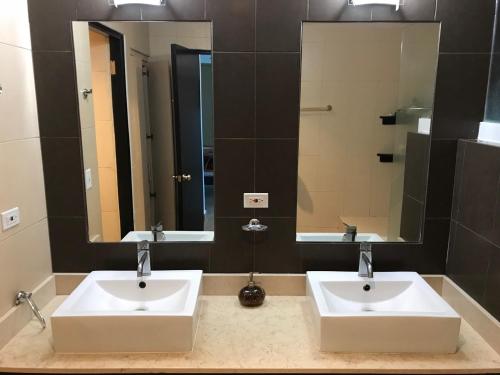 two sinks in a bathroom with two mirrors at Playa Blanca Beach front Condo in Río Hato