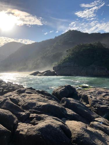 a rocky beach with the ocean and mountains in the background at Pousada Colibri in Trindade