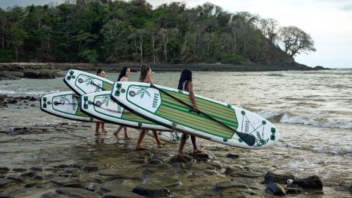 a group of girls carrying surfboards on a beach at Hostel-Island Paradise, Saboga Lodge and Villa Noelia in Panama City