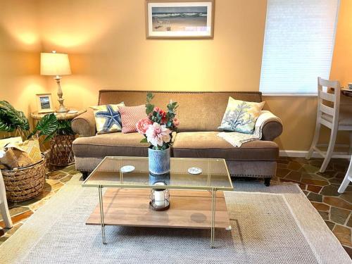 a living room with a couch and a table with flowers at Beach gem! Hot Tub/EV/2bd/3.7mi beach/.5mi outlets in Rehoboth Beach