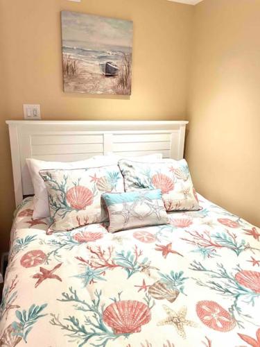 a bed with a floral comforter and pillows at Beach gem! Hot Tub/EV/2bd/3.7mi beach/.5mi outlets in Rehoboth Beach