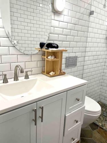 a bathroom with a sink and a mirror and a toilet at Beach gem! Hot Tub/EV/2bd/3.7mi beach/.5mi outlets in Rehoboth Beach