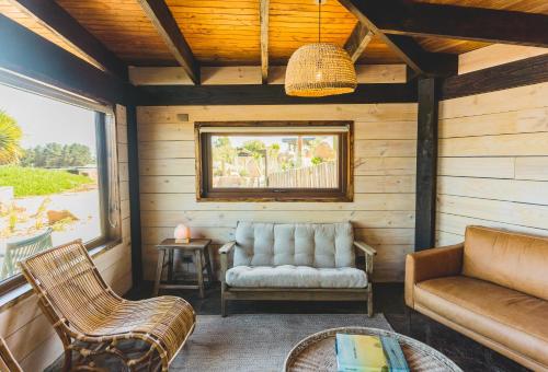 a screened in porch with a couch and chairs at Cuarzo Lodge in Pichilemu