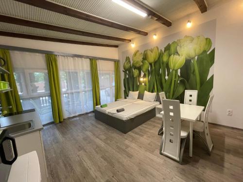 a room with a bed and a table and a flower mural at Tutti Apartman in Balatonlelle
