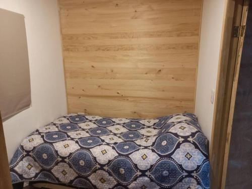 Dormitorio pequeño con cama con pared de madera en Casa Leon, en Puerto Varas
