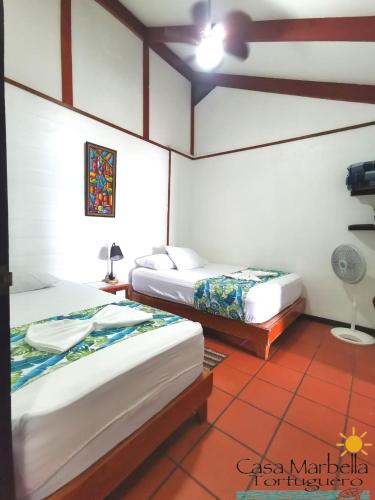 a room with two beds and a fan at Casa Marbella in Tortuguero