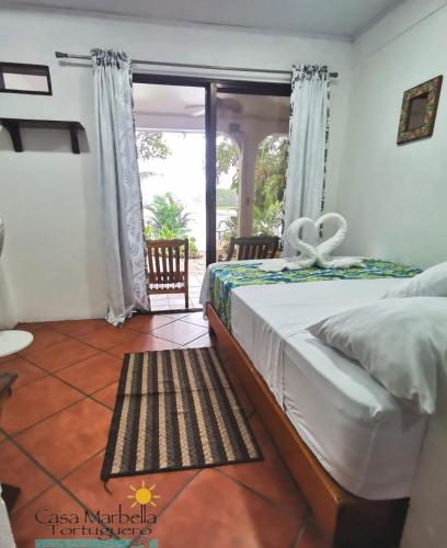a bedroom with a bed and a large window at Casa Marbella in Tortuguero