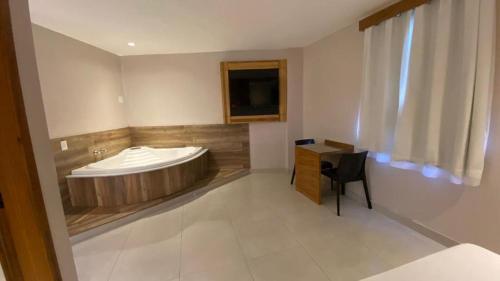 a bathroom with a tub with a table and a chair at Verona Hotel in Rio de Janeiro