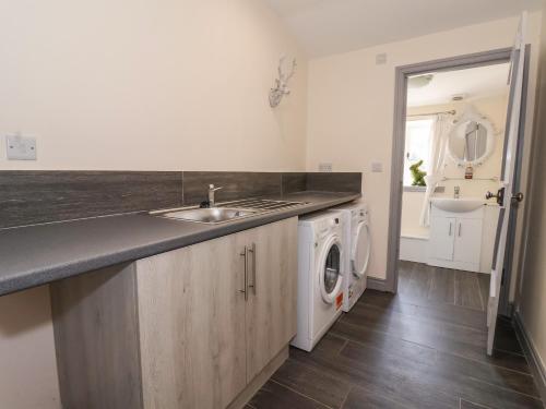 a kitchen with a sink and a washing machine at Cunliffe Barn in Shipley