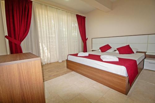 - une chambre avec un grand lit et des rideaux rouges dans l'établissement Nokta Kaya Suit Apart, Fethiye, Ölüdeniz, à Fethiye