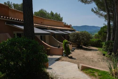 a building with a pathway next to a building with trees at Hôtel La Pinède in Saint-Marcellin-lès-Vaison