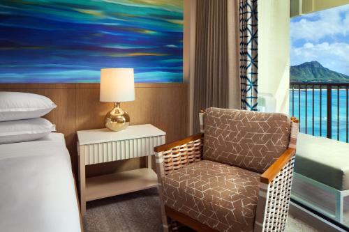 a bedroom with a bed and a chair and a window at Sheraton Waikiki Beach Resort in Honolulu