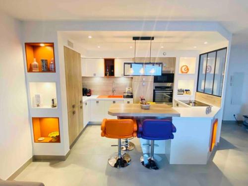 une cuisine avec un îlot avec trois tabourets de bar dans l'établissement Luxueux T3 Piscine et Vue Somptueuse, à Sète