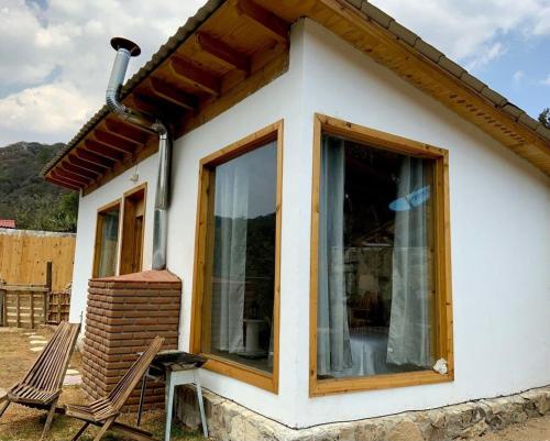 a small house with two chairs in front of it at Cabaña El Tepozan en Real del Monte in Mineral del Monte