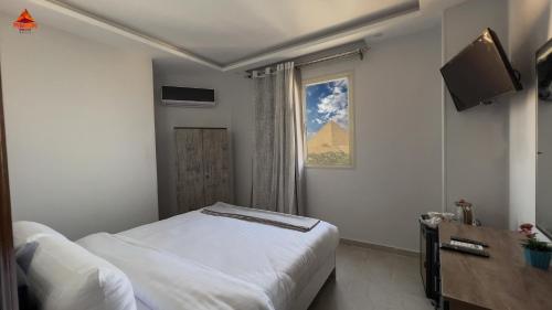 a hotel room with a bed and a television at Pyramids Tower view inn in Nazlat as Sammān