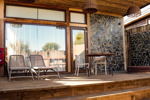 a deck with chairs and a table and a window at Cuarzo Lodge in Pichilemu