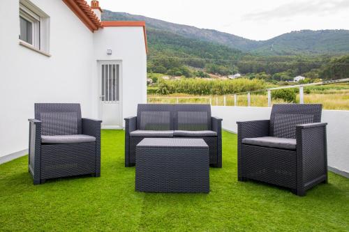 3 chaises et une table sur une terrasse avec pelouse dans l'établissement HOGAR DEL MAR, à Oia