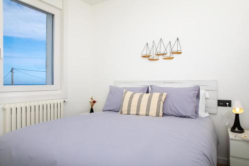 a white bedroom with a large bed with a window at HOGAR DEL MAR in Oia