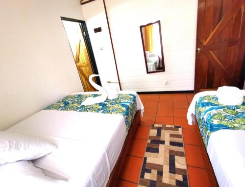 a room with two beds and a mirror at Casa Marbella in Tortuguero