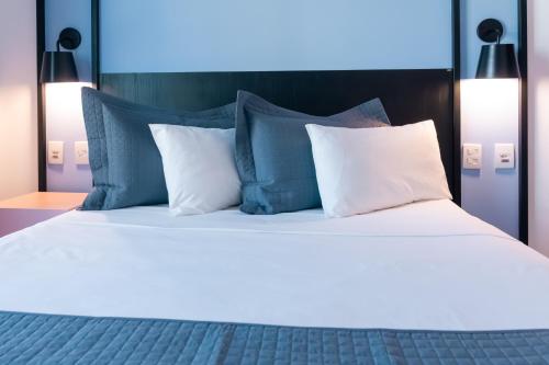 uma cama grande com almofadas azuis e brancas em ibis Styles Goiania Marista em Goiânia