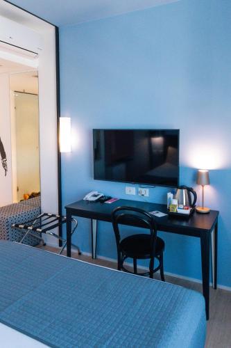a room with a desk with a television and a bed at ibis Styles Goiania Marista in Goiânia