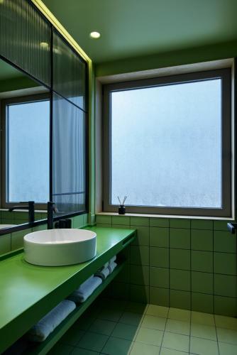 a green bathroom with a sink and two windows at DWELL - Elegant City Stay in Athens