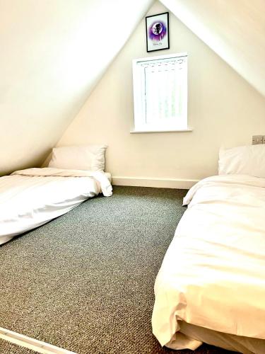 two beds in a attic room with a window at Pixie Cottage in Stoborough