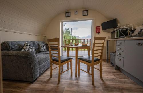 uma sala de estar com um sofá, uma mesa e cadeiras em Pinemarten Lodge em Roybridge