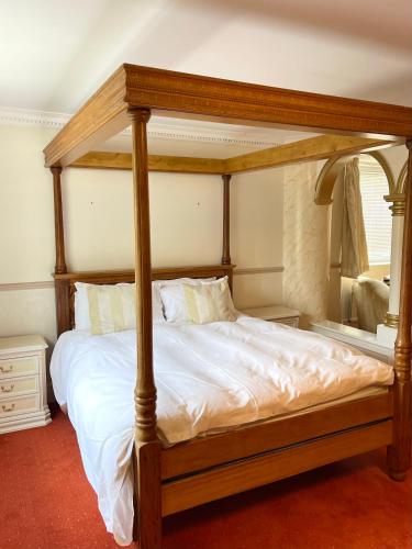 a bedroom with a canopy bed with white sheets at Arrandale Lodge in Norwich
