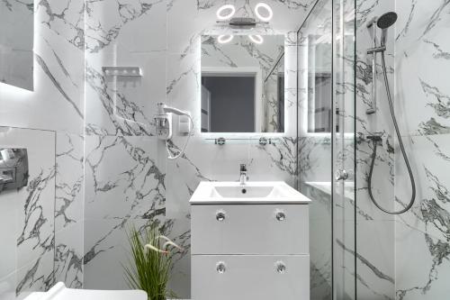 a white bathroom with a sink and a shower at Stawa Villa & Apart in Świnoujście