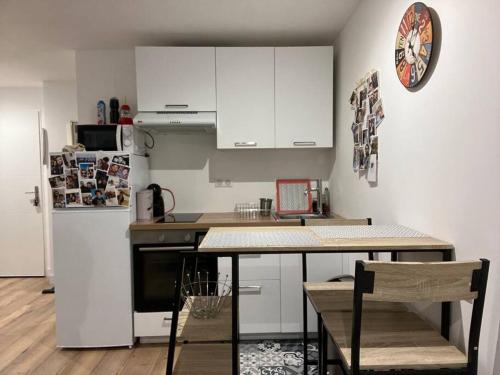 a kitchen with white cabinets and a table and a refrigerator at Studio centre village in Bocognano