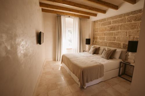 a bedroom with a bed and a brick wall at Casa Aura Hotel in Vejer de la Frontera