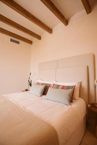 a bedroom with a large white bed with wooden ceilings at Casa Aura Hotel in Vejer de la Frontera