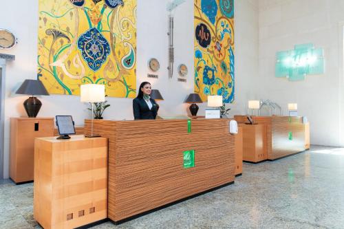a woman is standing behind a counter in a room at Holiday Inn Kuwait by IHG in Kuwait