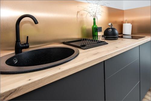 a bathroom counter with a black sink and a bottle at Rytas cozy apartment in the guest house with the terrace and the stunning view to the river side in Birštonas