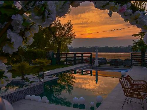 a swimming pool with a sunset in the background at Casa Palmera in Novi Sad