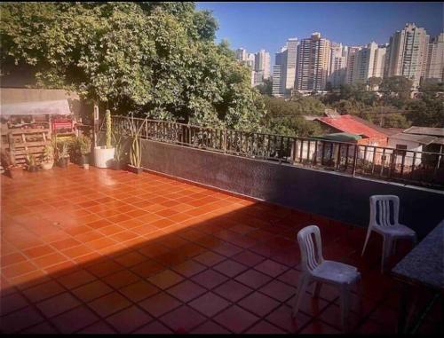 2 Stühle auf einem Balkon mit Stadtblick in der Unterkunft Quarto confortável lago igapó in Londrina