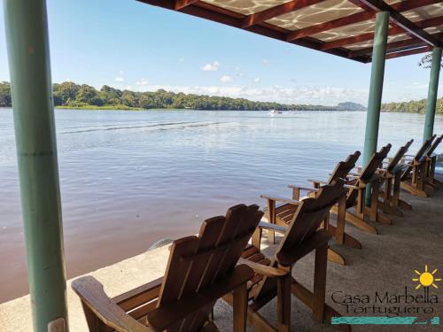a row of chairs sitting on the shore of a river at Casa Marbella in Tortuguero