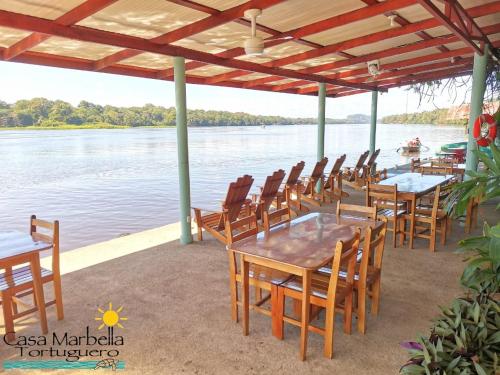 a group of tables and chairs on the water at Casa Marbella in Tortuguero