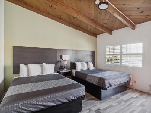 a bedroom with two beds and a window at Discovery Inn Monterey Bay in Seaside