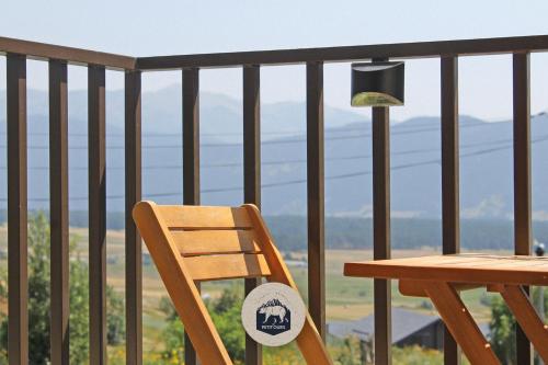 einem Holzstuhl neben einem Tisch auf einem Balkon in der Unterkunft Le Petit Ours & Le Petit Cerf - Studios vue lac & montagnes in Les Angles