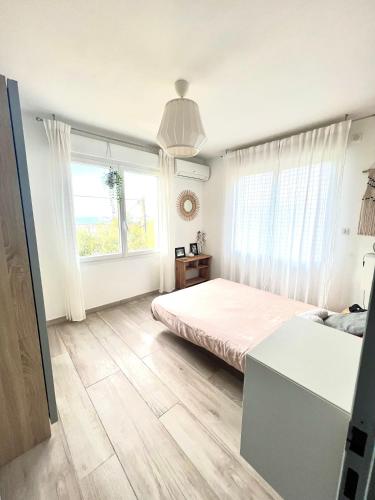 une chambre avec un lit et une grande fenêtre dans l'établissement Maison 3 ch 6 pers Sanary vue dominante mer - plage à 400 m - accès piscine - jardin - wifi - terrasse - pergola bioclimatique - climatisation - location par semaine complète, à Sanary-sur-Mer