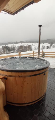 un bain à remous en bois avec de la neige au sol dans l'établissement Góralskie Domki na Podhalu - z jacuzzi, à Maniowy